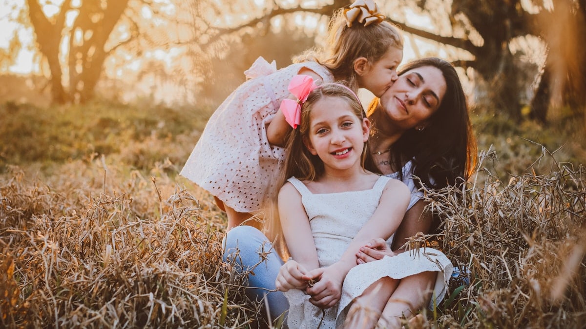 a family of three sitting in a field of tall grass